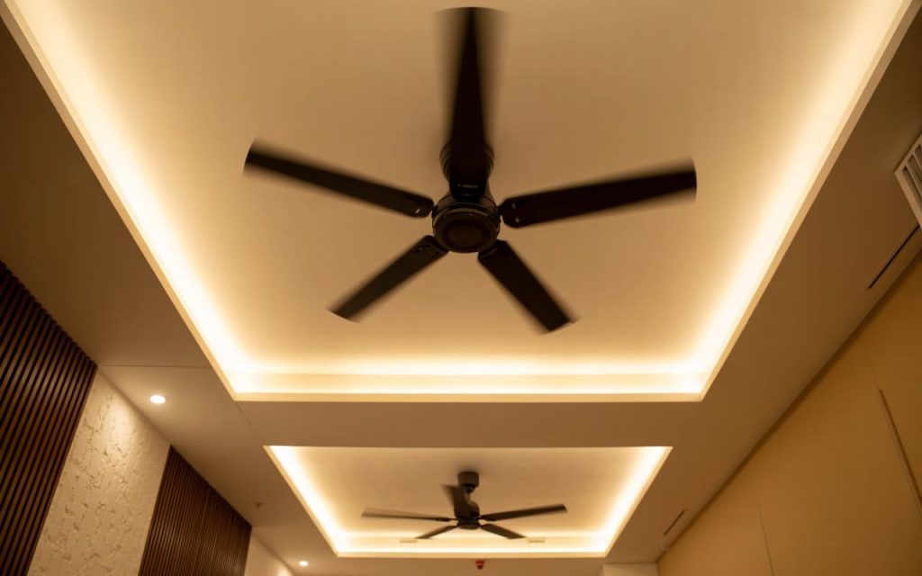 A minimalist simple false ceiling design for hall with tray panels and warm LED lighting.