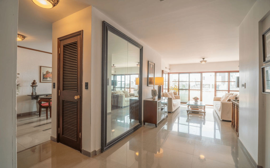 Bright entryway decor with large mirror, glossy floor and open living space creating home entrance
