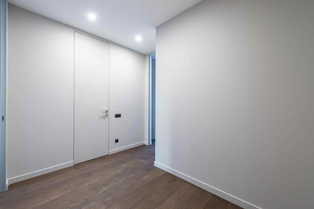 Flush hidden door design matching white wall